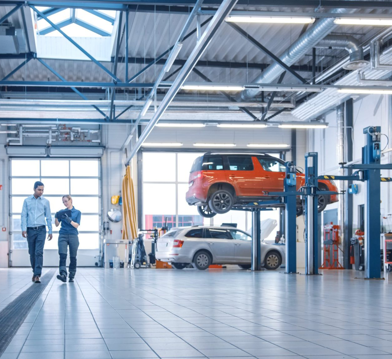 vehicles in a garage with mechanics walking through talking about work